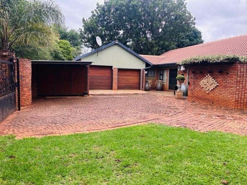 Front exterior view of a brick house featuring a double garage, attached carport, and a paved driveway with a small front lawn.