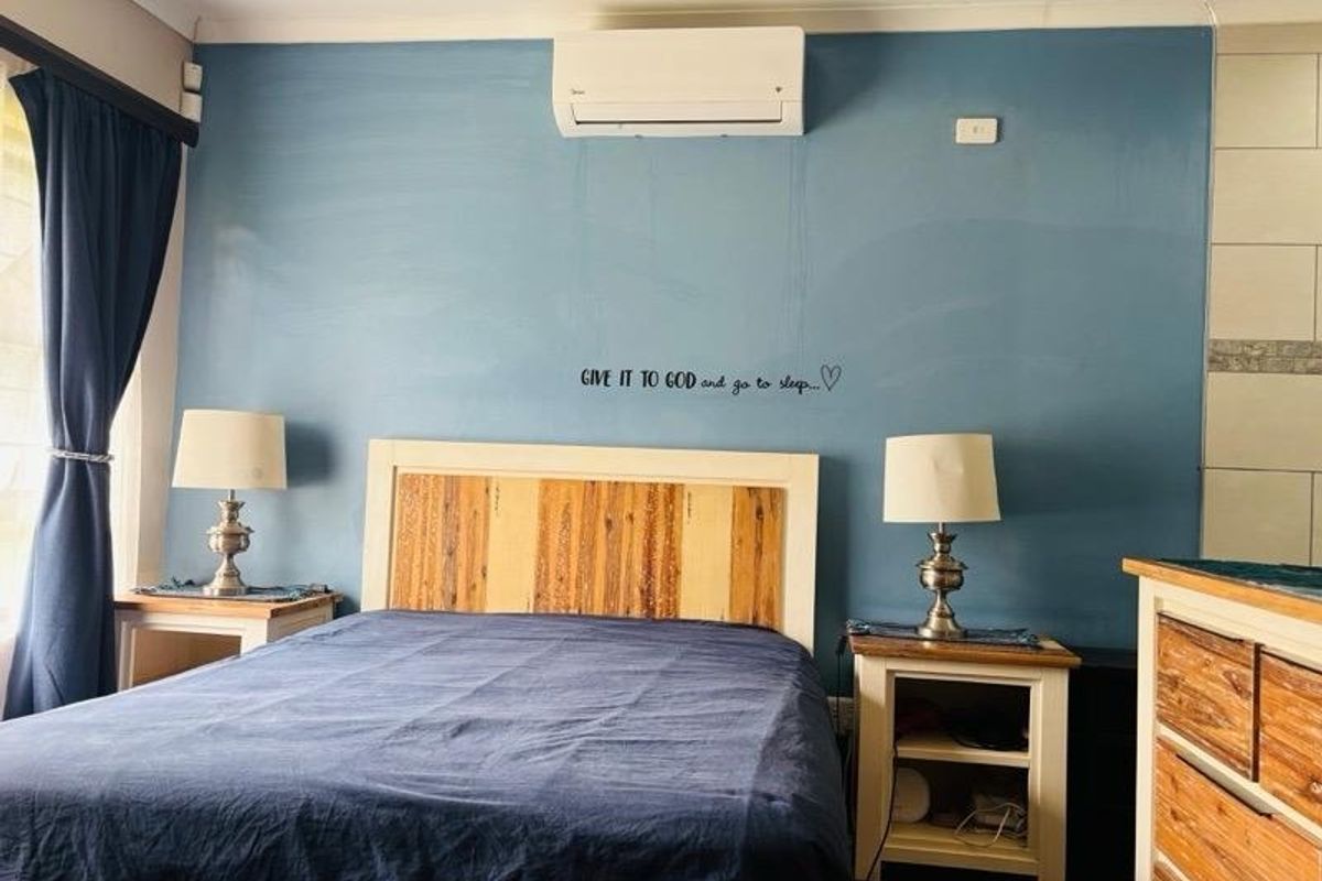 A bedroom featuring a blue accent wall, split-system air conditioning, and recessed lighting.