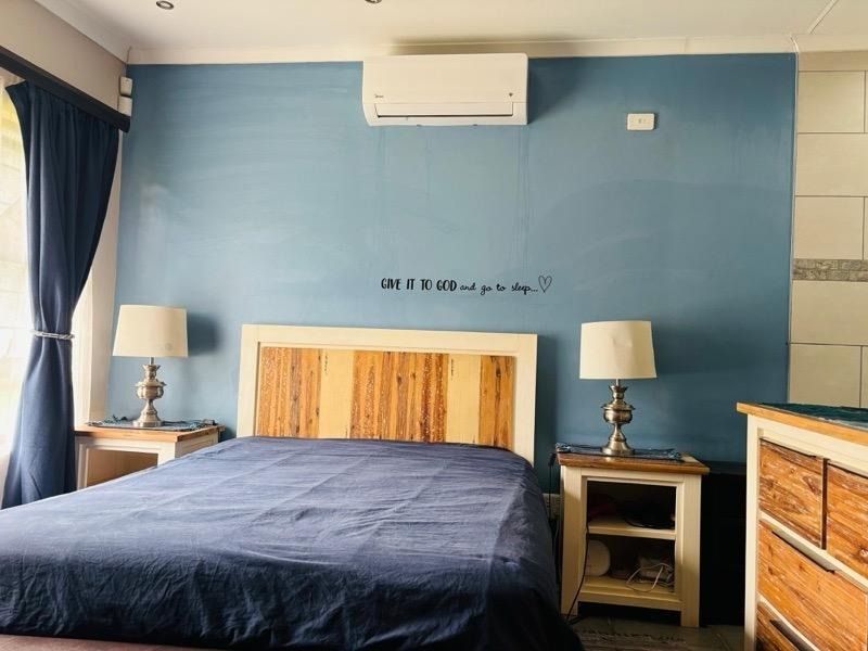 A bedroom featuring a blue accent wall, split-system air conditioning, and recessed lighting.