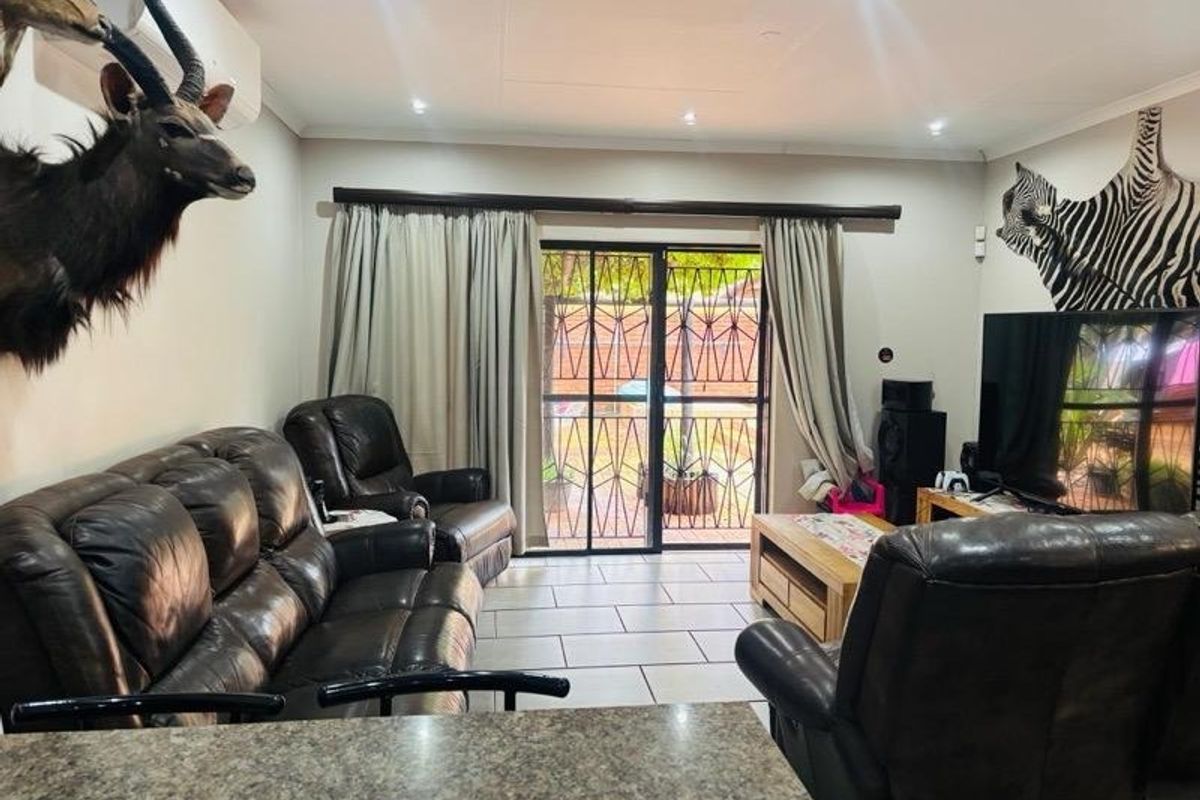 A living room featuring tiled flooring, recessed lighting, and a sliding glass door with security gate leading to the exterior.
