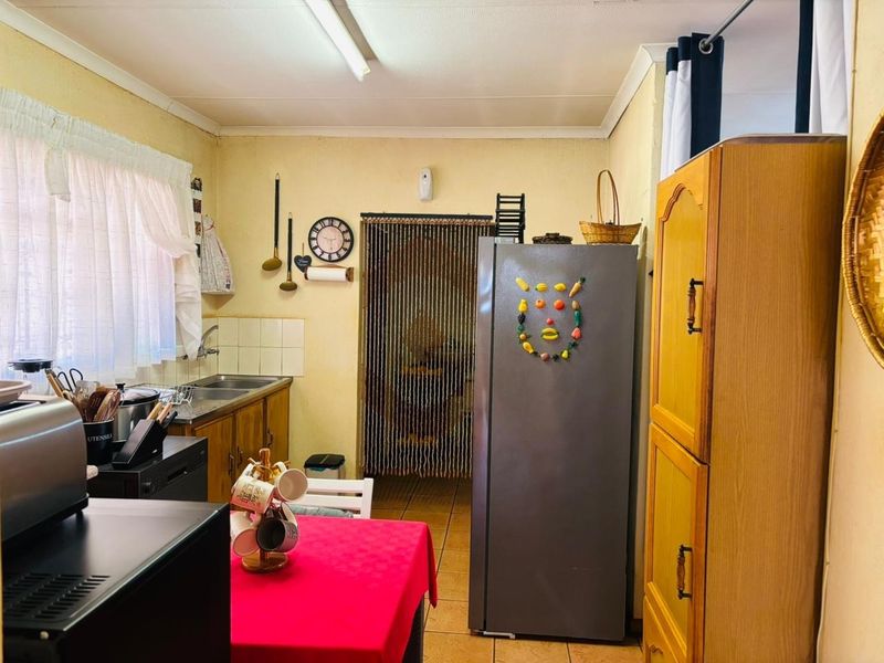 A functional kitchen featuring built-in wooden cabinetry, a stainless steel sink, and tiled flooring, offering potential for a modern renovation.