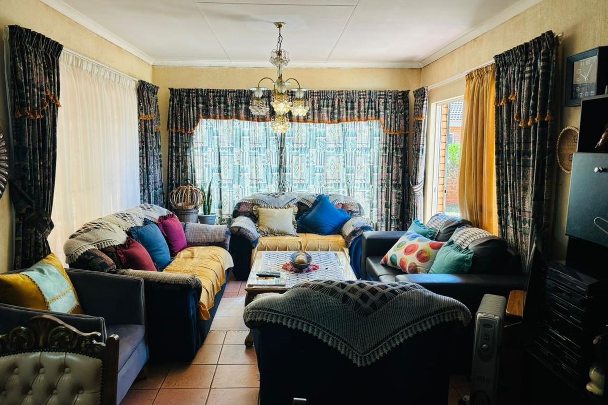 A traditional living room featuring tiled flooring, a central chandelier, and coved ceilings, offering a comfortable and classic living space.