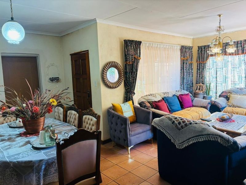 Open-plan living and dining area featuring tiled flooring, decorative ceiling cornices, and classic lighting fixtures, offering a functional and connected layout.