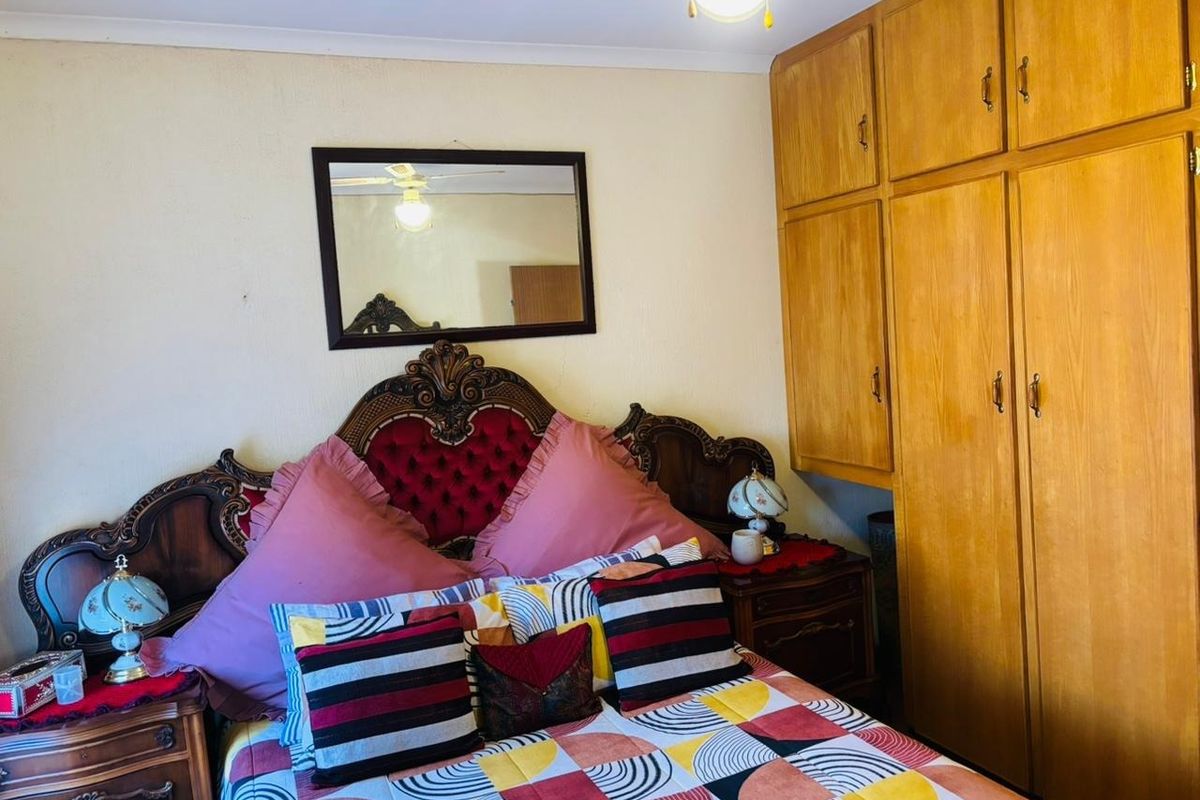 A bedroom featuring built-in wooden cupboards and a ceiling fan, providing functional storage and climate control.