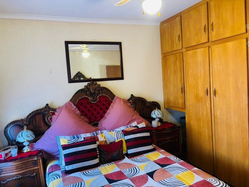 A bedroom featuring built-in wooden cupboards and a ceiling fan, providing functional storage and climate control.