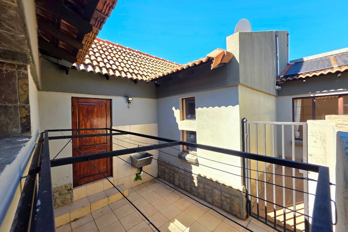 A rear courtyard area featuring tiled flooring, a utility sink, and access to the main dwelling via a timber door and security gate.