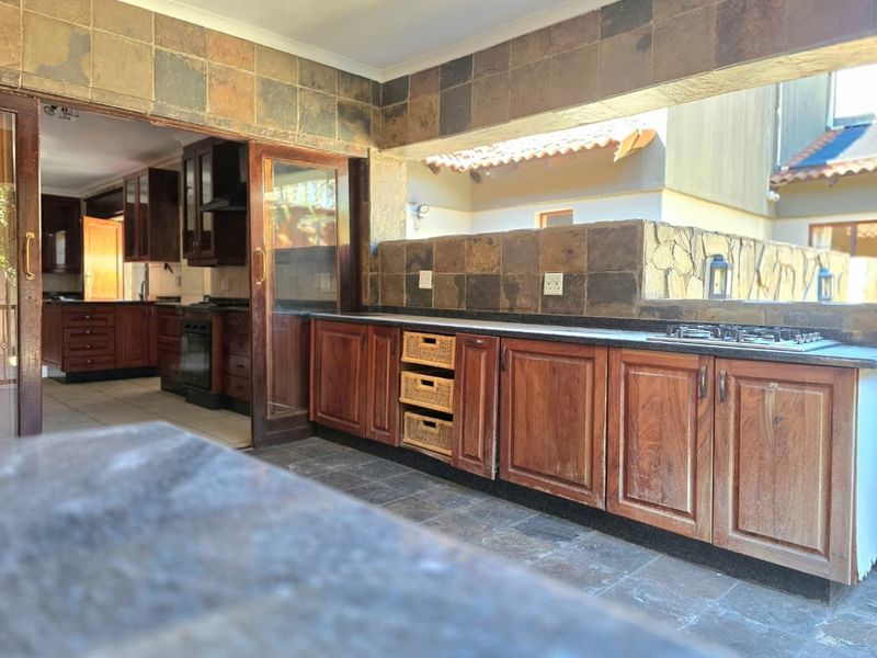 Covered outdoor patio featuring built-in cabinetry, stone countertops, and a gas hob, providing a functional space for outdoor cooking and entertaining.
