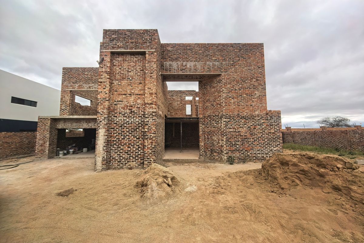 A residential property under construction featuring exposed brickwork and structural framing, currently in the early stages of development.