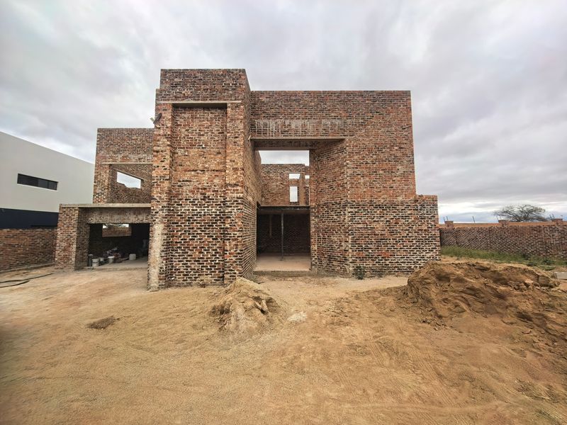 A residential property under construction featuring exposed brickwork and structural framing, currently in the early stages of development.