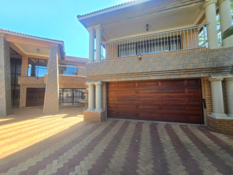 Front exterior view of a multi-story house featuring a wooden garage door, stone-clad facade, and a balcony with metal railings.