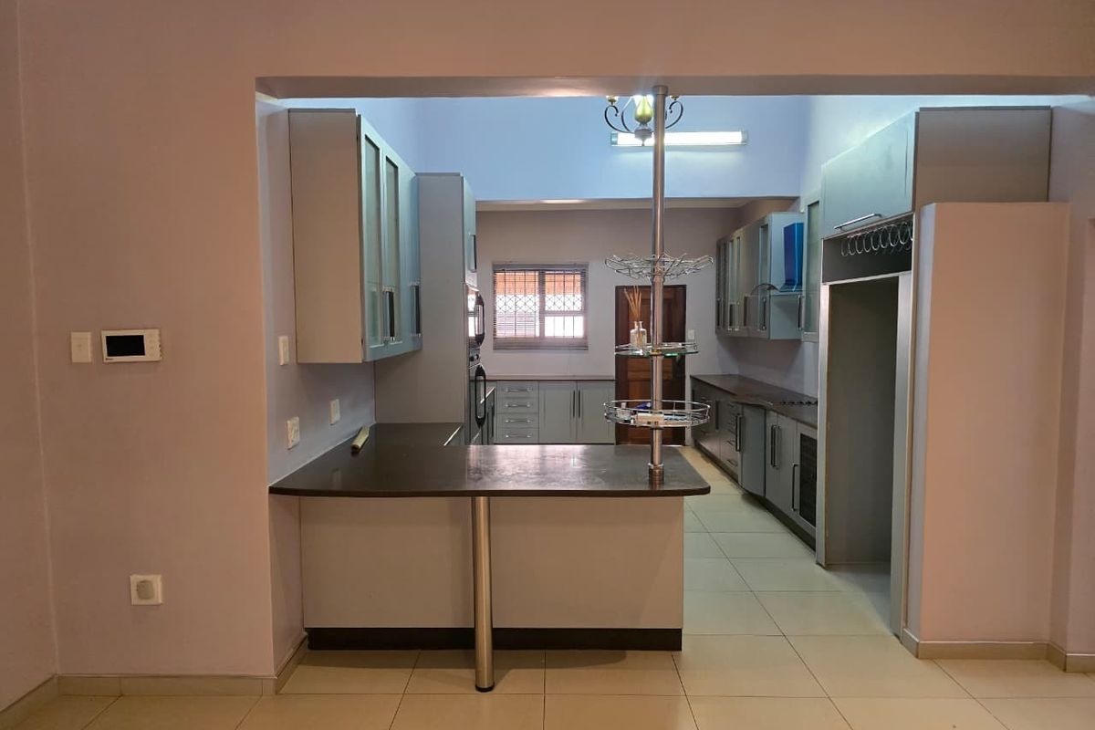 A functional kitchen featuring built-in cabinetry, laminate countertops, a breakfast bar, and tiled flooring, offering a clean and practical layout.