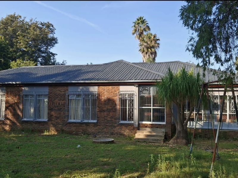 Rear view of a single-story brick house featuring a tiled roof, security bars on windows, and a small concrete entrance step.