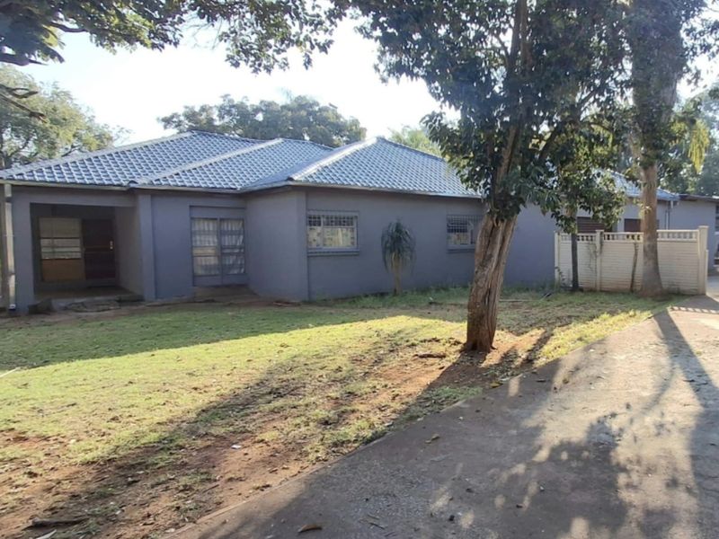 Front view of a single-story house featuring a tiled roof, security bars on windows, and a concrete driveway leading to the entrance.