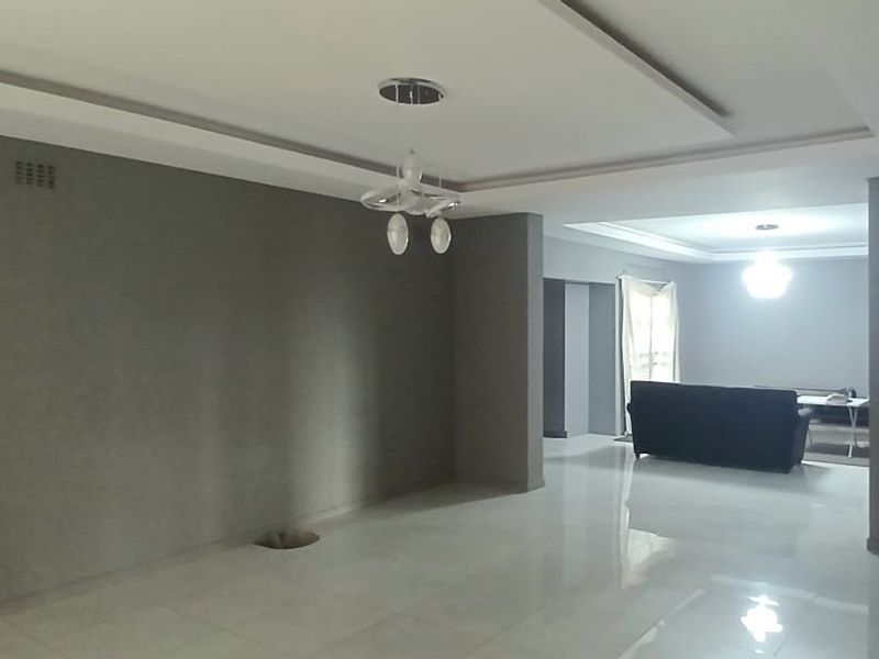 Spacious open-plan living area featuring modern tiled flooring, recessed ceiling details, and contemporary lighting fixtures, offering a clean and versatile layout.