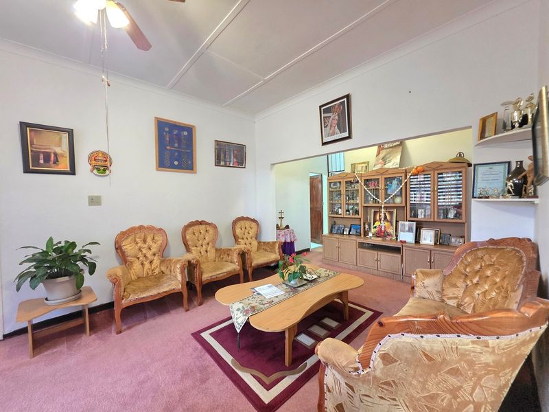 A traditional living room featuring a ceiling fan and built-in wooden display cabinetry, offering a classic layout with carpeted flooring.