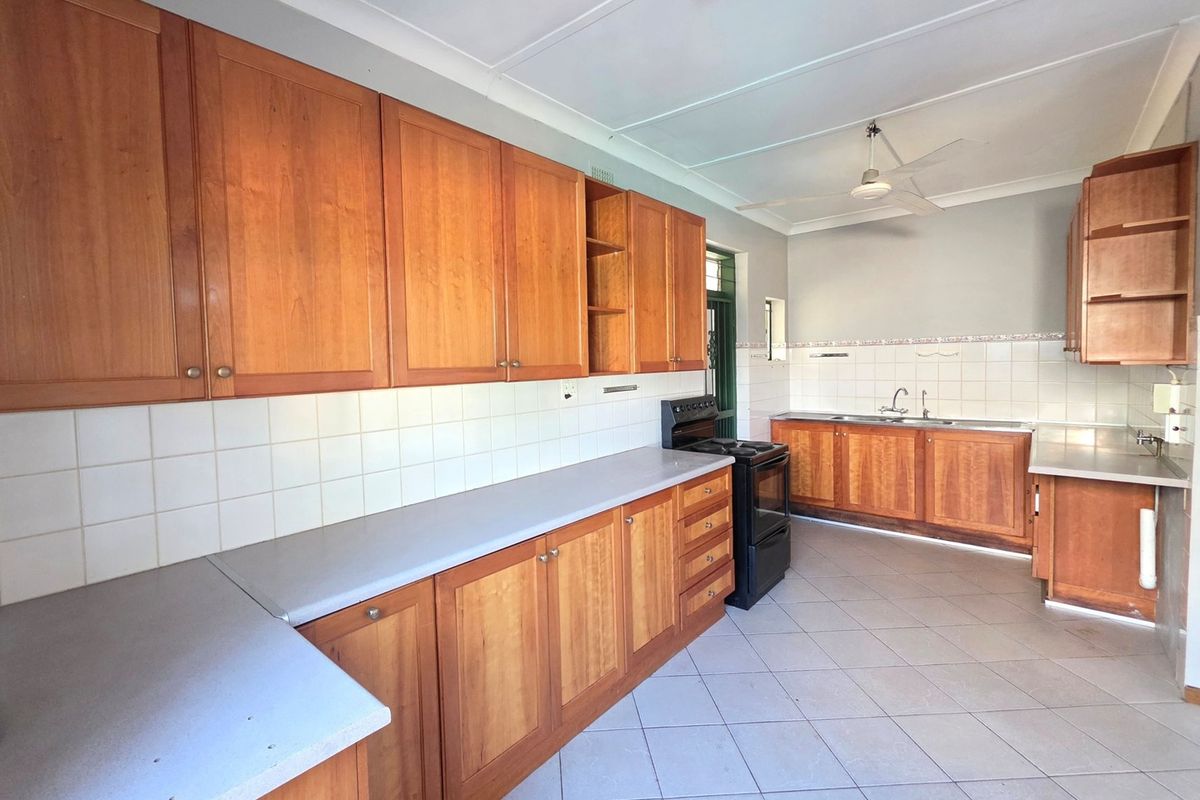 Spacious kitchen featuring extensive wooden cabinetry, laminate countertops, tiled backsplash, and a freestanding stove, offering a functional layout with ample storage space.