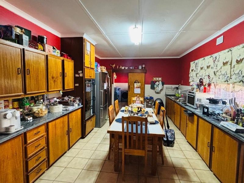 A spacious kitchen featuring extensive wooden cabinetry, laminate countertops, tiled flooring, and a functional layout with integrated oven and sink area.
