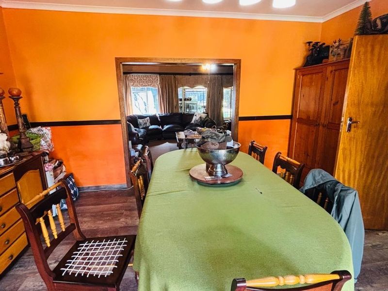 Dining room featuring laminate flooring and coving, with an open transition to the adjacent living area.