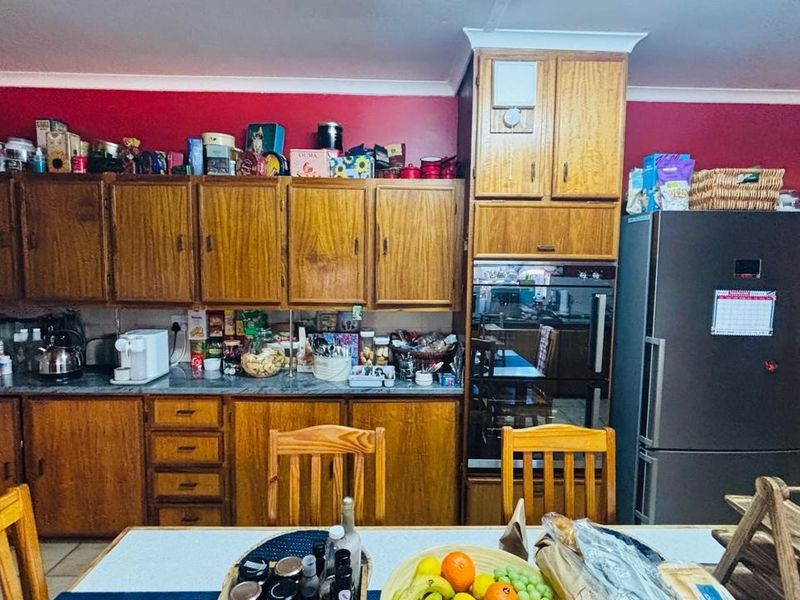 A traditional kitchen featuring extensive wooden cabinetry, built-in oven, and laminate countertops, offering a functional layout with potential for modern cosmetic updates.