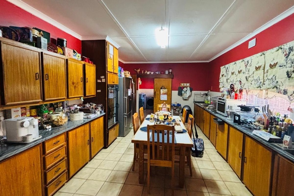 A spacious kitchen featuring extensive wooden cabinetry, laminate countertops, tiled flooring, and a functional layout with integrated oven and sink area.