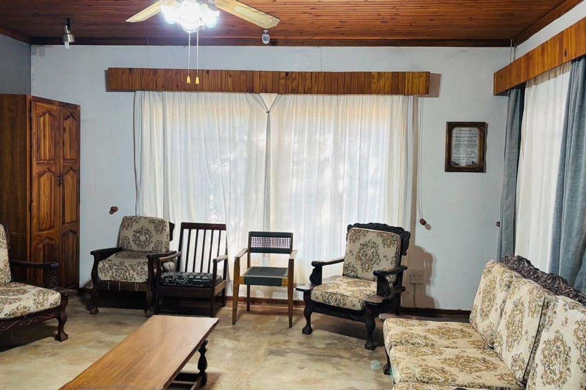 Living room featuring a timber ceiling with a central fan and timber pelmets, currently finished with exposed concrete flooring.