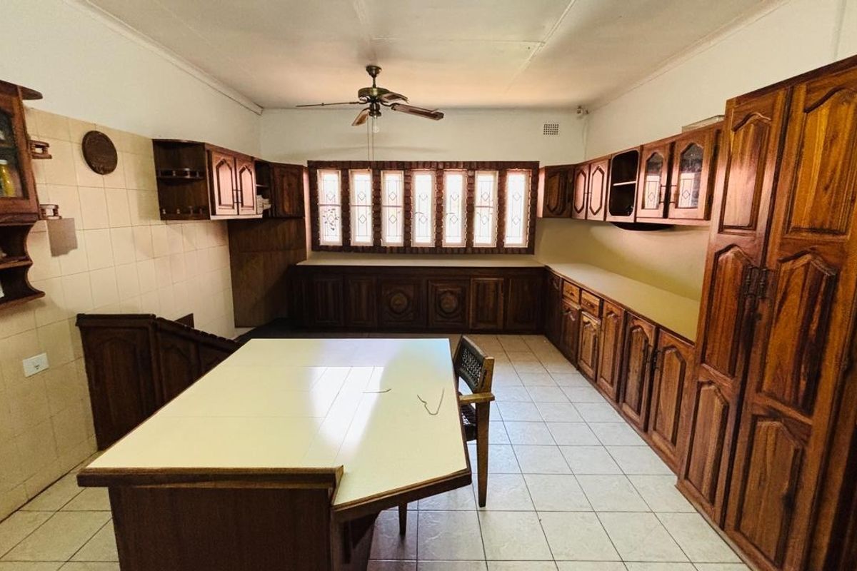 A spacious kitchen featuring extensive wooden cabinetry, tiled flooring, a central island, and a ceiling fan, offering a traditional layout with ample storage.