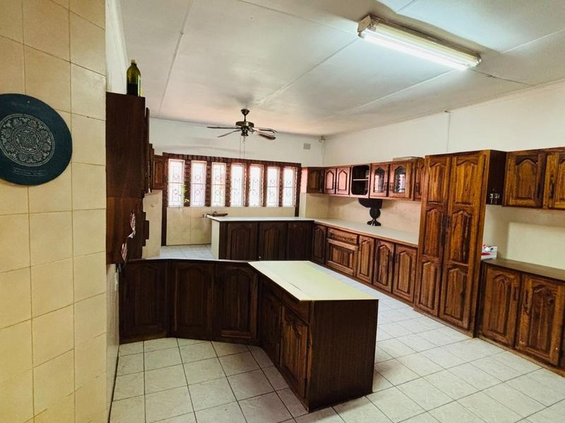 Spacious kitchen featuring extensive wooden cabinetry, tiled flooring, and a functional layout with ample storage space, ready for modern updates.