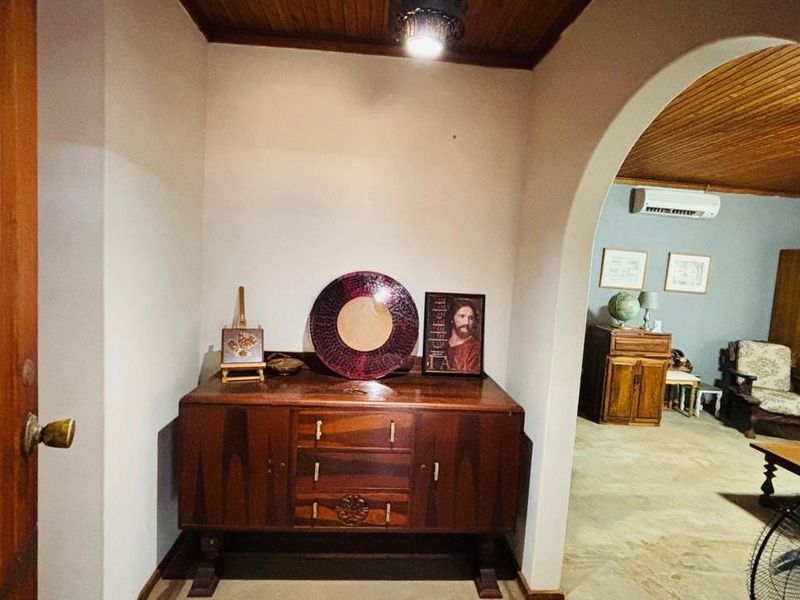 An entry foyer featuring a timber ceiling and an arched opening leading into the main living area, which includes a wall-mounted air conditioning unit.