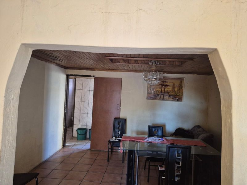 Dining area featuring a timber ceiling, tiled flooring, and a decorative archway leading to an adjacent room.