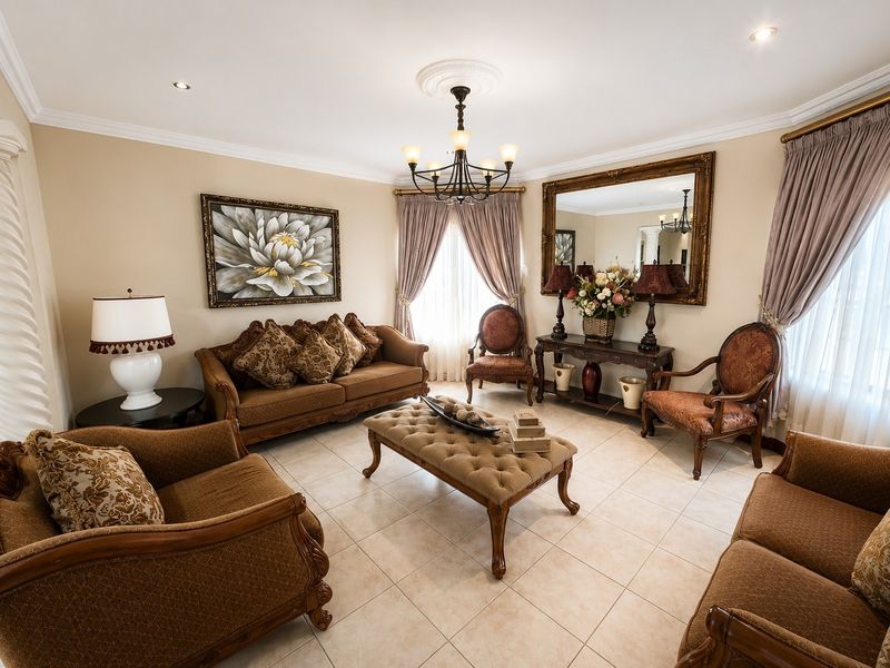 A well-maintained living room featuring neutral tiled flooring, recessed downlighting, and decorative ceiling detailing, providing a comfortable and classic formal seating area.