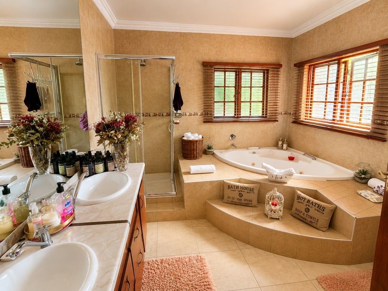 Spacious bathroom featuring a double vanity, a raised built-in bathtub, and a separate shower enclosure with neutral wall and floor tiling.