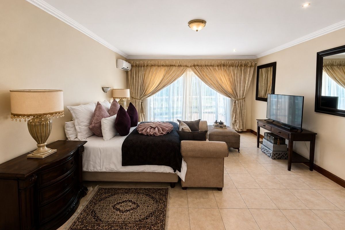 Spacious bedroom featuring neutral tiled flooring, crown molding, and a wall-mounted air conditioning unit, offering a comfortable and well-maintained living space.