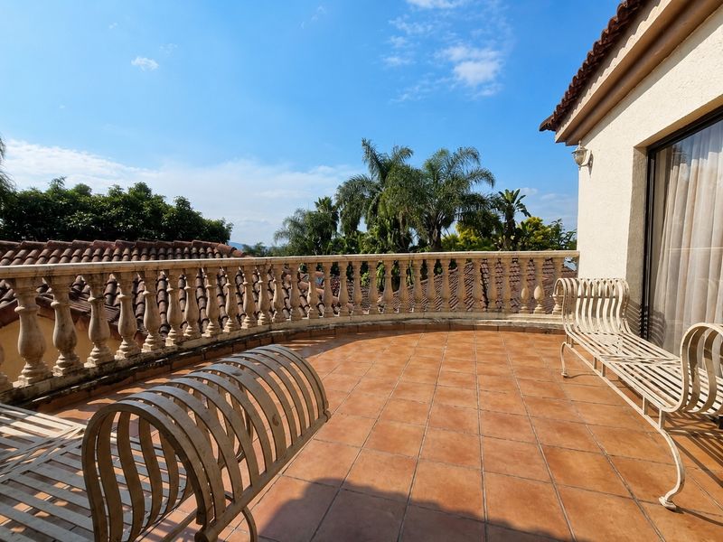 Spacious balcony featuring terracotta tiling and a classic stone balustrade, offering an open-air space with views of the surrounding greenery.