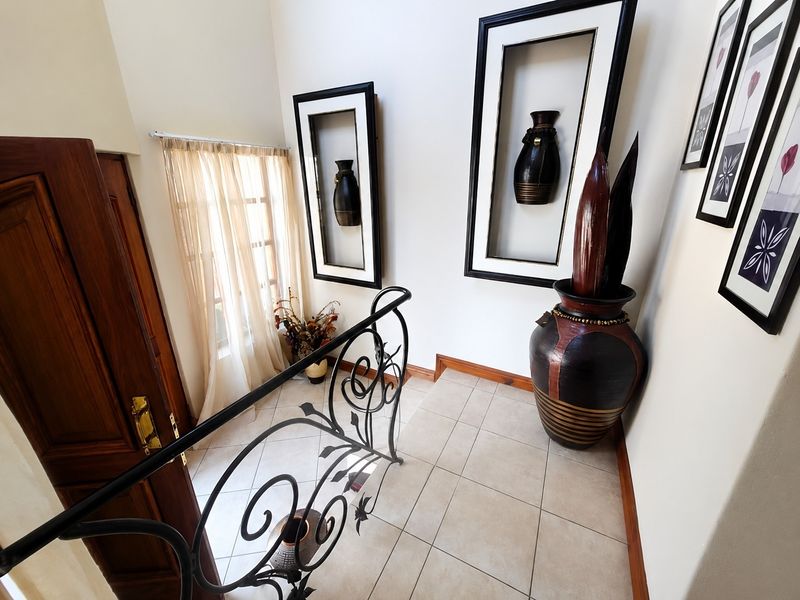 A bright hallway featuring tiled flooring, a decorative wrought iron balustrade, and built-in wall niches for display.
