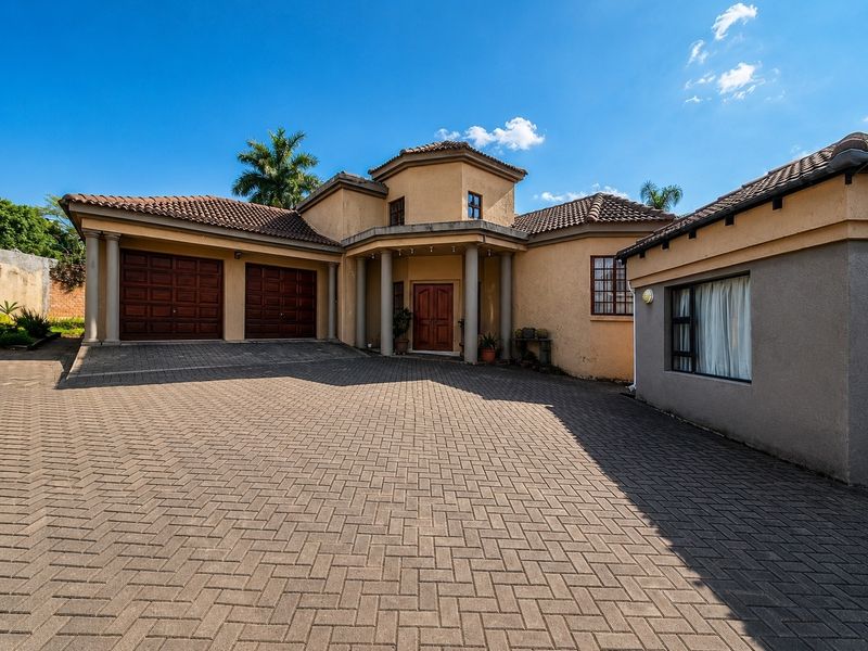 Front elevation of a house featuring a large paved driveway, double garage, and a covered entrance with architectural columns.