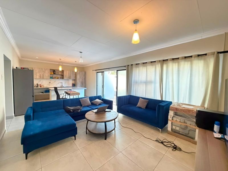 An open-plan living and kitchen area featuring tiled floors, modern cabinetry, and sliding glass doors that provide access to the outdoor space.