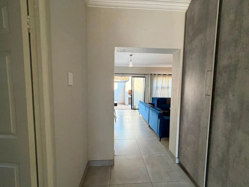 A bright hallway featuring modern tiled flooring and a large built-in cupboard, providing a clean transition into the main living area.