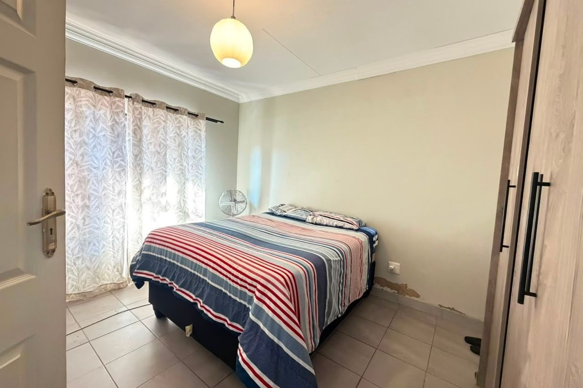 A bedroom featuring tiled flooring, a built-in wardrobe, and coving, showing visible signs of wall surface damage and peeling paint.