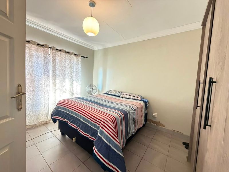 A bedroom featuring tiled flooring, a built-in wardrobe, and coving, showing visible signs of wall surface damage and peeling paint.