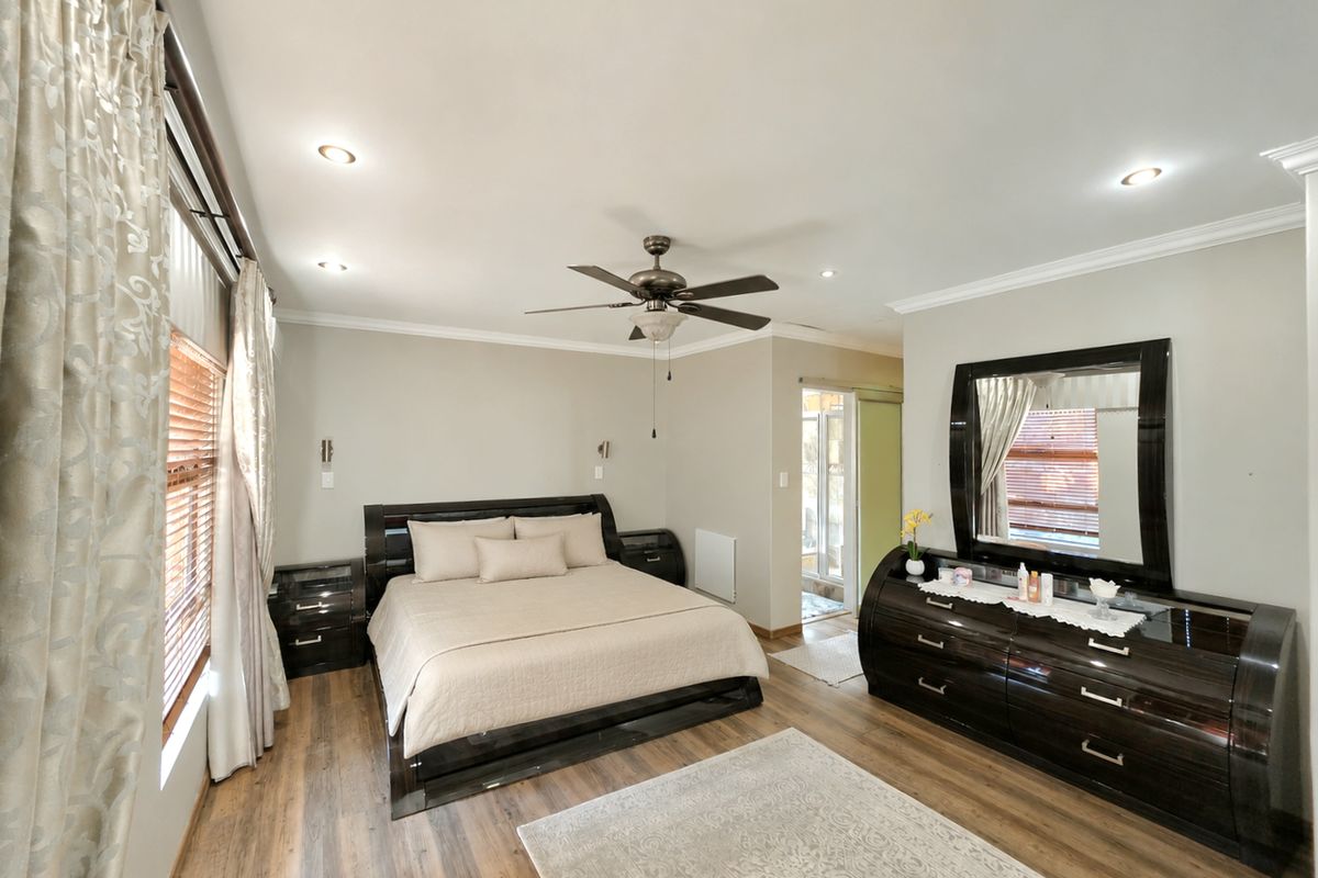 Spacious bedroom featuring laminate flooring, recessed lighting, a ceiling fan, and crown molding, with direct access to an adjoining space.