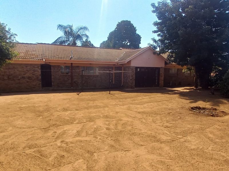 A view of the rear exterior of the house featuring a brick facade, tiled roof, and a large, unlandscaped garden area.