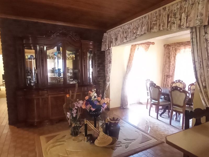 Living area featuring a timber ceiling, stone feature wall, and tiled flooring, providing a traditional aesthetic with potential for modern updates.