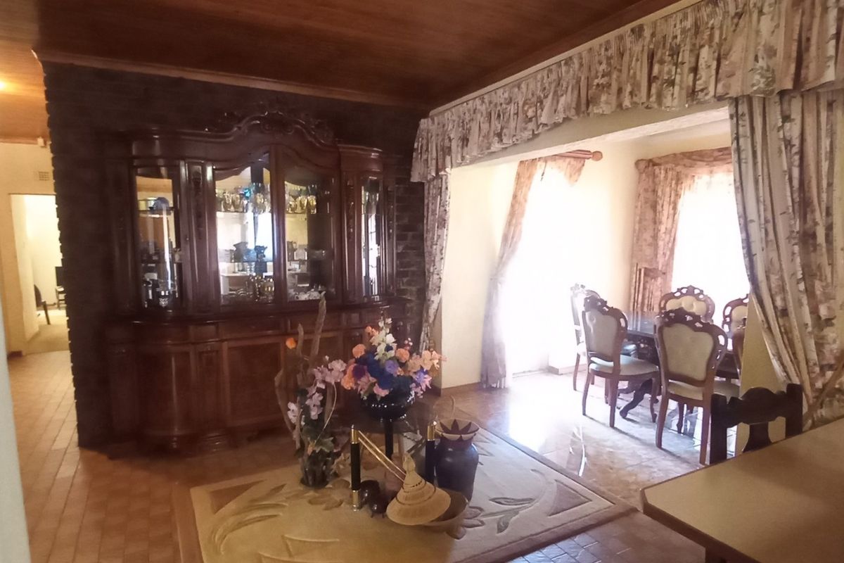 Living area featuring a timber ceiling, stone feature wall, and tiled flooring, providing a traditional aesthetic with potential for modern updates.