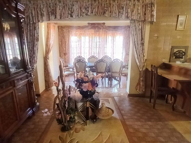 Open plan living and dining area featuring tiled flooring and a built-in breakfast bar, offering a traditional layout with potential for modernization.