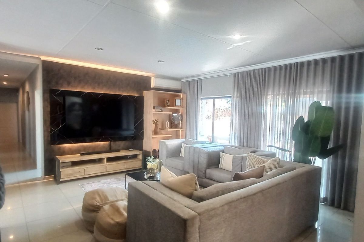 A modern, well-maintained living room featuring a sleek built-in media wall, recessed lighting, and tiled flooring, creating a comfortable and contemporary living space.