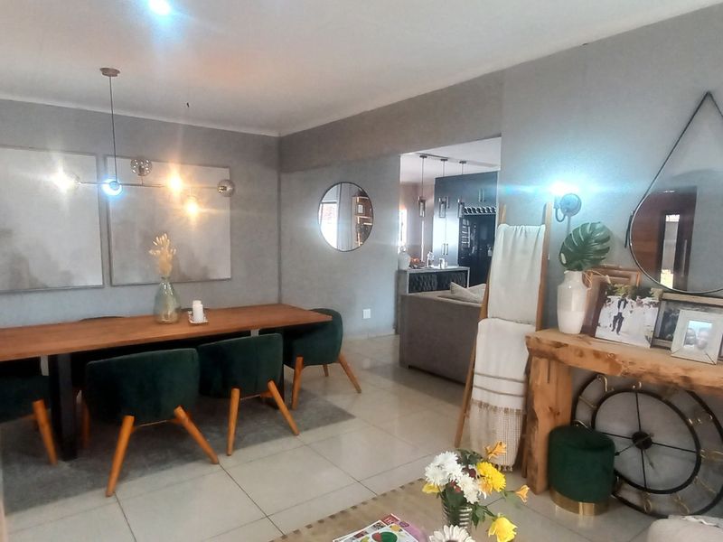 Spacious open-plan living and dining area featuring neutral grey walls, large format floor tiles, and modern lighting fixtures.