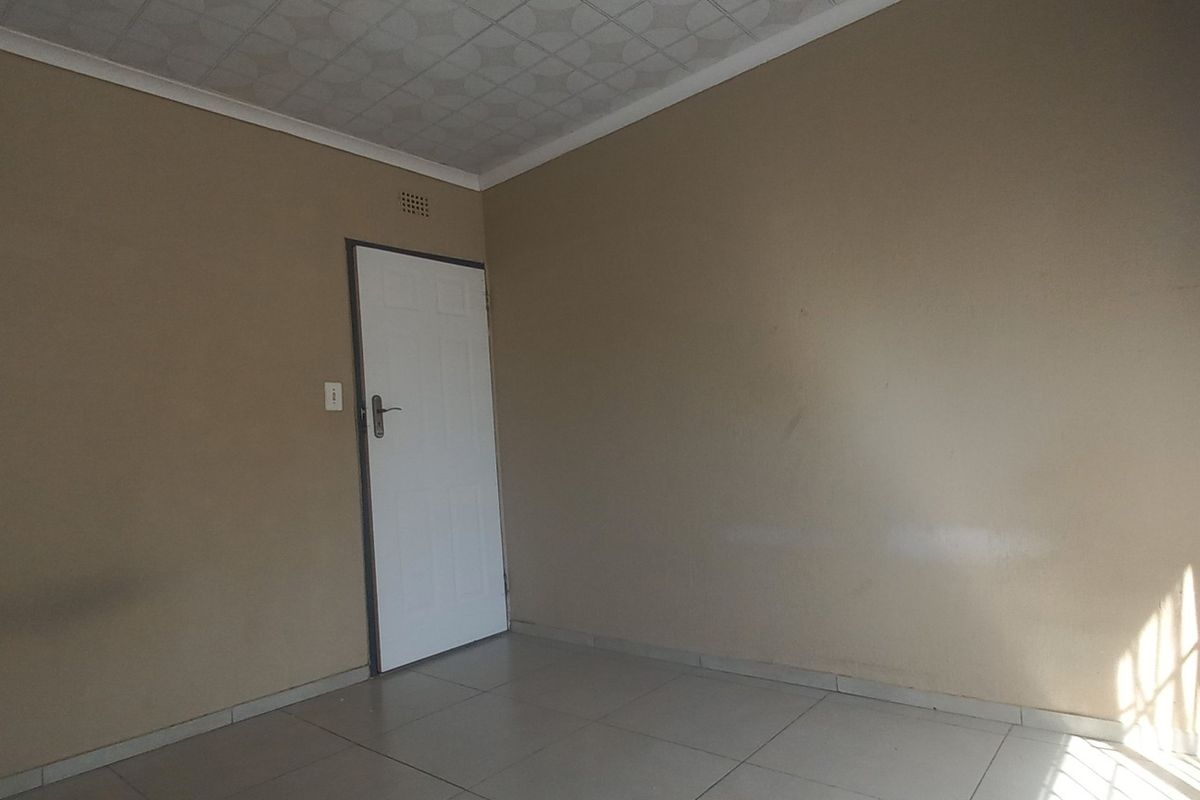 An empty bedroom featuring tiled flooring, a standard internal door, and patterned ceiling tiles, offering a blank canvas for potential interior updates.