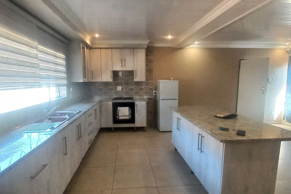 Modern kitchen featuring light-toned cabinetry, stone countertops, a central island, and integrated appliances with tiled flooring and recessed lighting.