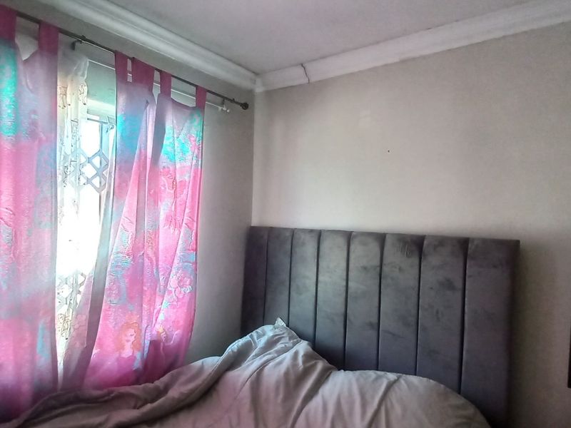 A bedroom featuring a built-in wardrobe and decorative ceiling cornice, with a security gate visible on the window.