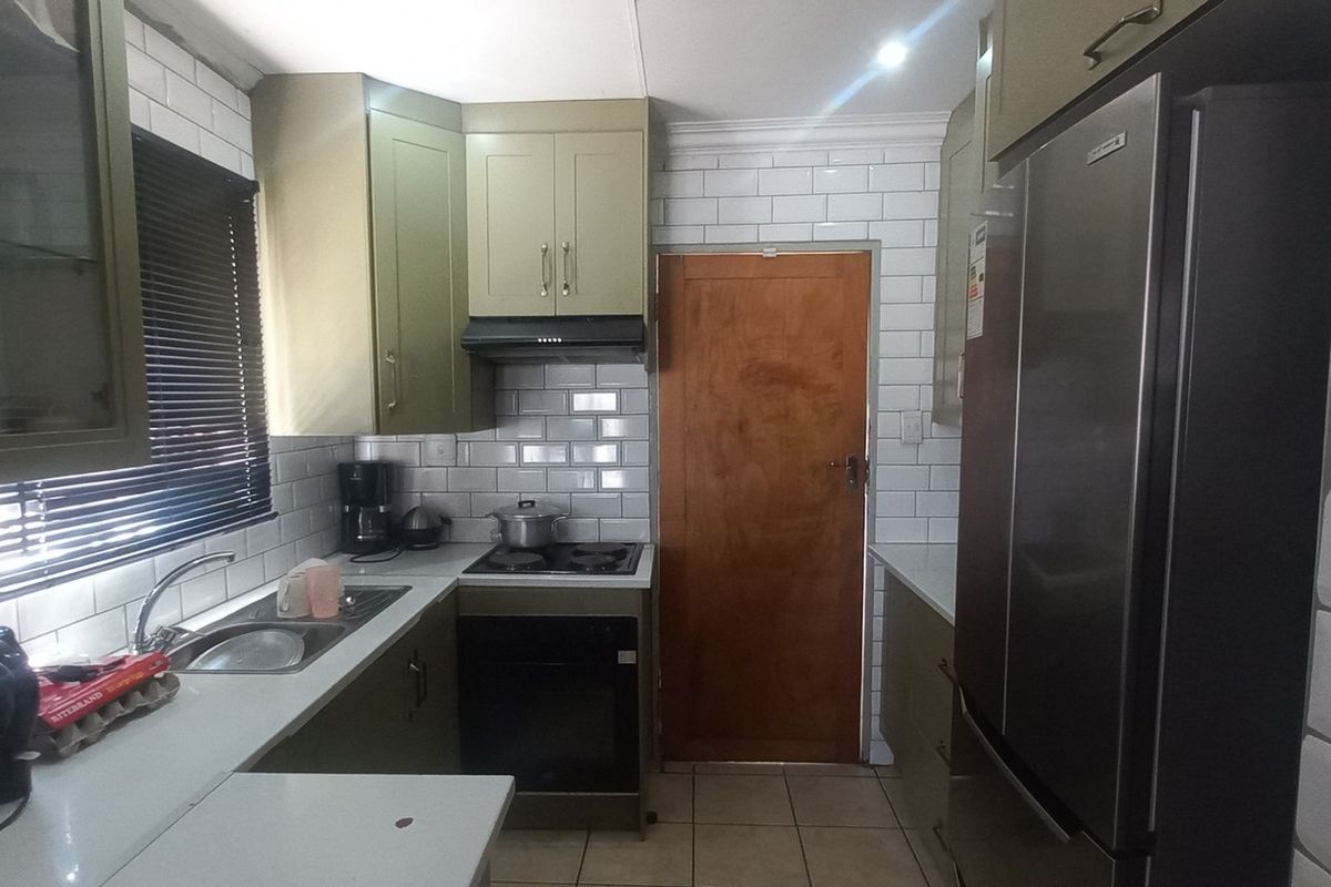 A functional kitchen featuring olive-toned cabinetry, white subway tile backsplash, built-in oven with hob, and tiled flooring.